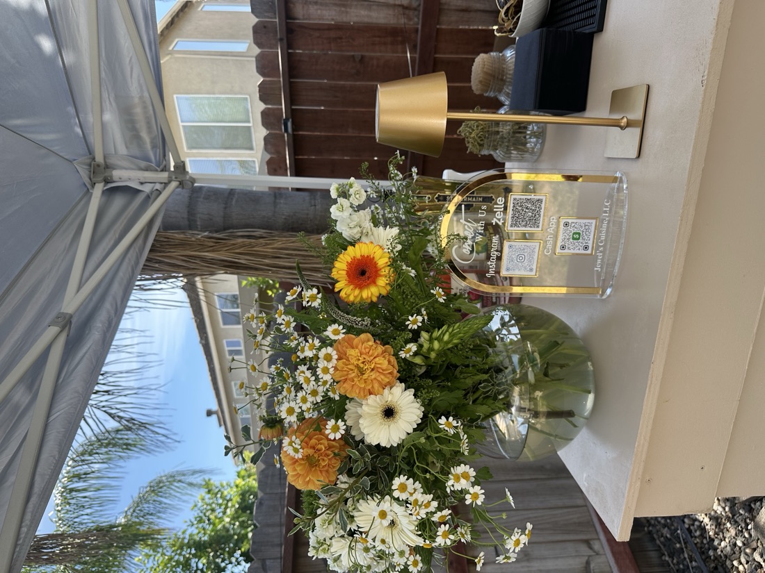 Bar-top vignette with a wildflower bouquet, gold cordless lamp, and Jewel's Cuisine LLC QR connect sign for Instagram, Zelle, and Cash App